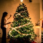 Decorating Budget - child standing in front of Christmas tree with string lights