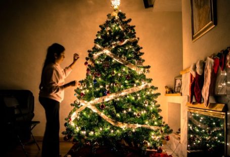 Decorating Budget - child standing in front of Christmas tree with string lights