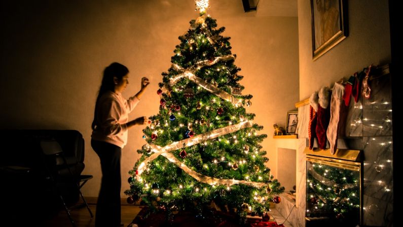 Decorating Budget - child standing in front of Christmas tree with string lights
