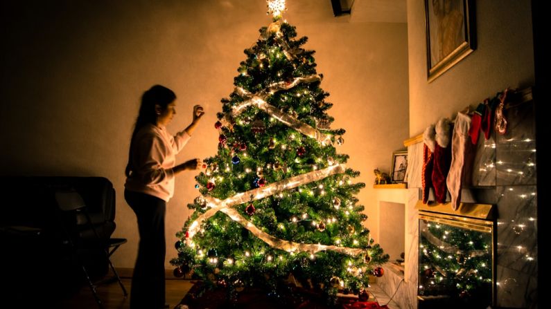 Decorating Budget - child standing in front of Christmas tree with string lights