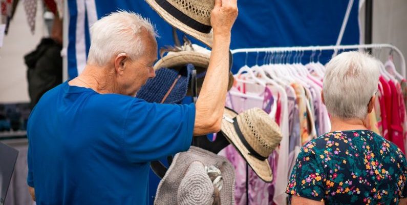 Clothing Shopping - A man and woman are looking at hats at a market
