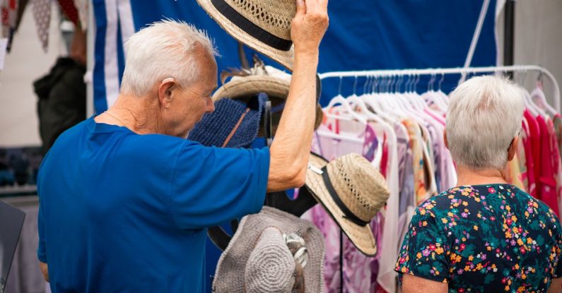 Clothing Shopping - A man and woman are looking at hats at a market