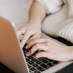 Discount App - Crop woman typing on laptop on bed