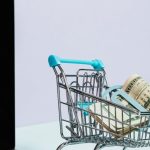 Electronics Sale - Shopping Cart with Money on Top of a Laptop
