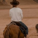 Buying Guide - A woman riding a horse down a dirt road