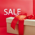 Luxury Discount - Cardboard Box with Red Ribbon Beside A Sale Sign