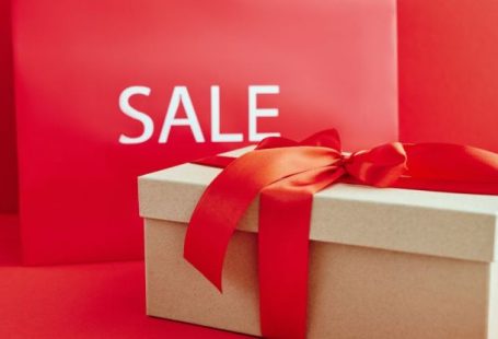 Luxury Discount - Cardboard Box with Red Ribbon Beside A Sale Sign