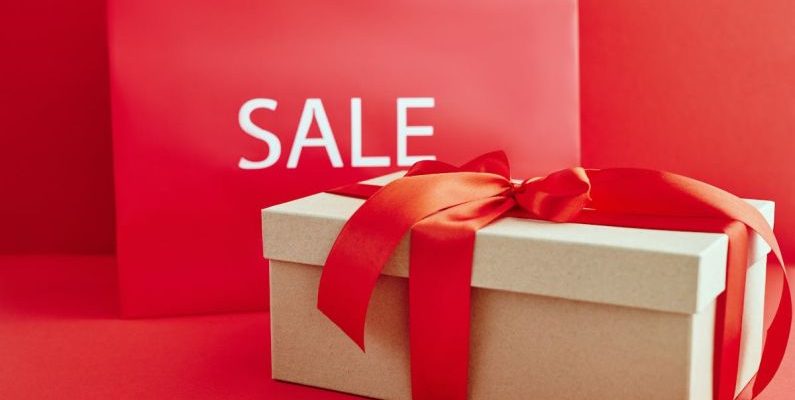 Luxury Discount - Cardboard Box with Red Ribbon Beside A Sale Sign
