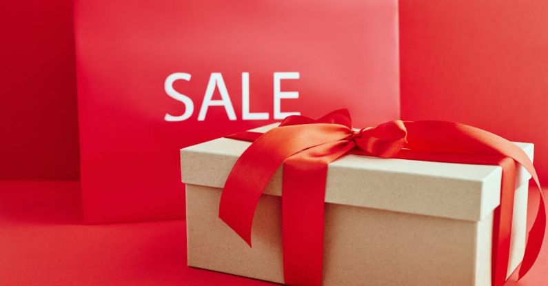 Luxury Discount - Cardboard Box with Red Ribbon Beside A Sale Sign