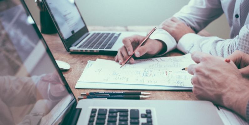 Coupon Website - person holding pencil near laptop computer