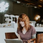 Online Deals - woman sitting on brown wooden chair while using silver laptop computer in room