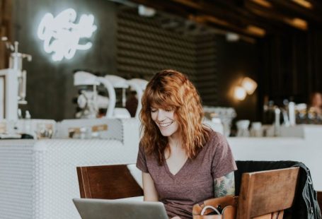 Online Deals - woman sitting on brown wooden chair while using silver laptop computer in room