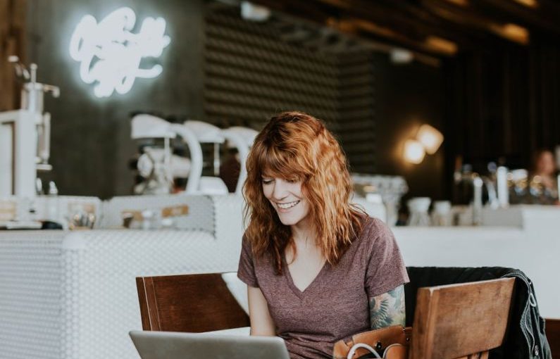 Online Deals - woman sitting on brown wooden chair while using silver laptop computer in room