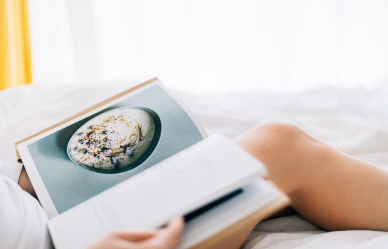 Weeknight Recipes - person holding open magazine while laying on bed